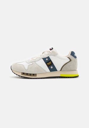Sneaker caratterizzati da una combinazione di tessuto bianco e suede beige, con un pannello blu e un accento giallo sulla suola. Design atletico classico.