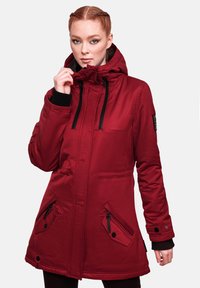 Chaqueta parka roja con capucha, cordones ajustables, detalles de hardware negro, puños elásticos y bolsillos laterales. Textura de tela suave.