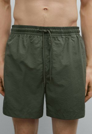 Olivgrüne Badehose aus leichtem Material mit einem elastischen Bund und Zugband, ohne sichtbare Taschen oder Muster.