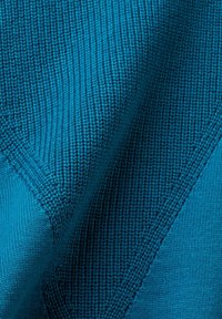 Close-up of blue knitted fabric showing detailed ribbed and smooth stitch patterns with folded texture.