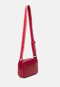 Red leather crossbody bag with a rectangular shape. Features a wide, multicolored stripe adjustable strap and a top zipper closure.
