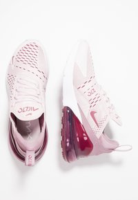 Tenisky Nike Air Max v světle růžové barvě s síťovinovým svrškem a gumovou podrážkou. Mají viditelné vzduchové polstrování v burgundské barvě a texturované akcenty.