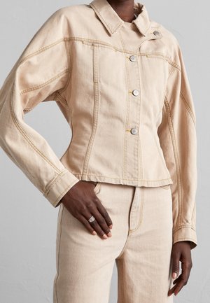 Veste en denim beige au design ajusté, grand col, boutons argentés et détails de couture jaunes. Texture lisse, longueur cropped.