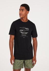 Camiseta negra de manga corta con estampado gráfico blanco; combinada con pantalones cortos verdes oliva con un patrón de hojas negras y bolsillos laterales.