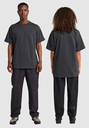 Mörkgrå oversized t-shirt med rund halsringning, i bomull. Bärs med vida svarta byxor med ett synligt nummer "223" på benet.