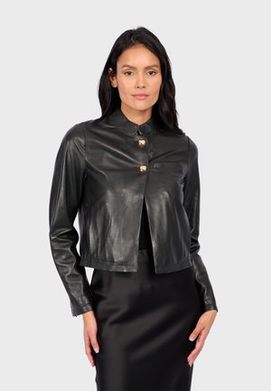 Veste en cuir noir raccourcie avec un col montant, comportant trois fermetures à boutons dorés et une petite poche poitrine. Texture lisse.