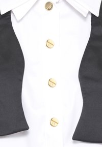 Camicia bianca con colletto in raso nero, caratterizzata da cinque bottoni rotondi dorati sul davanti. Tessuto liscio con una texture netta.