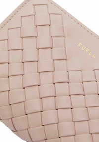 Tkaná kožená kabelka v jemně růžové barvě se čtvercovým vzorem. Zlaté logo "Furla" na boku, hladký povrch s pevnou strukturou.