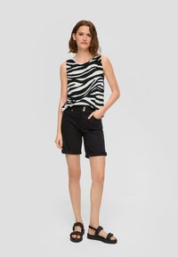 Zwarte shorts met omgeslagen manchetten gecombineerd met een mouwloos topje met een zwart-wit zebra print ontwerp. Lichtgewicht stof, casual fit.
