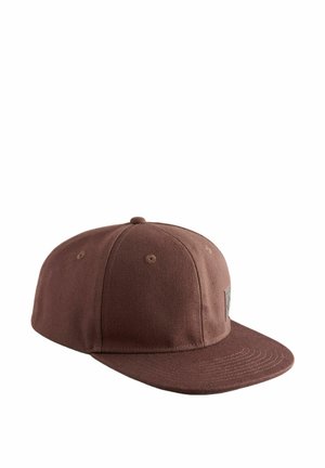 Brown cotton cap with a flat brim, textured fabric, and a small logo patch on the front panel. Six ventilation eyelets on top.