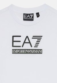 Hvit bomull T-skjorte med EA7 Emporio Armani-logo i svart trykk. Rund hals, korte ermer og glatt tekstur.