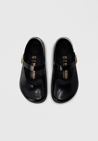 Μαύρα σανδάλια τύπου slip-on με λείο, γυαλιστερό φινίρισμα, με χρυσό λουράκι με αγκράφα στο επάνω μέρος του ποδιού. Το εσωτερικό φέρει λεπτομέρειες της μάρκας.