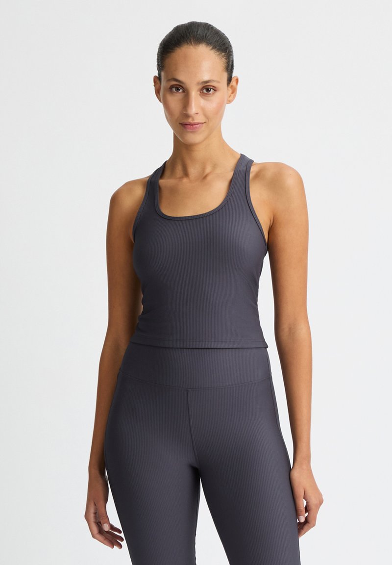 Grå ribbade sporttop med breda axelremmar och rundad halsringning, i kombination med matchande högmidjade leggings. Slät textur genom hela plagget.