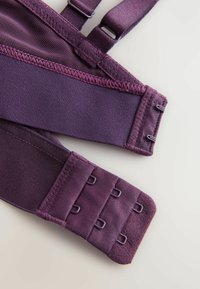 Lähikuva purppurasta rintaliivien hakasesta, jossa on koukku- ja silmukkakiinnitykset sekä säädettävät hihnat vaalealla taustalla.