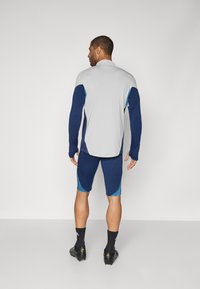 Sports apparel featuring a gray long-sleeve shirt with blue accents and matching navy shorts, designed for athletic use.
