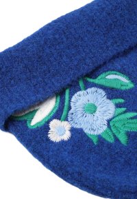 Tamaie albastră din fetru cu design floral brodat, având flori de culoare albastră deschisă și albă, frunze verzi și o suprafață texturată.