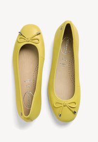 Gele leren balletschoenen met een afgeronde neus, een zijstrikaccent, metalen hardwaredetails en een zachte beige voering met perforaties.