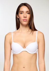 Reggiseno bianco imbottito con spalline sottili regolabili, texture liscia, design a scollatura profonda e chiusura con gancio al centro.