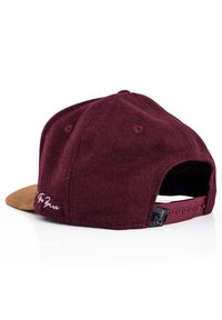 Cappello bordeaux con visiera in suede marrone, tessuto testurizzato, dettagli ricamati sul retro e chiusura a scatto regolabile.