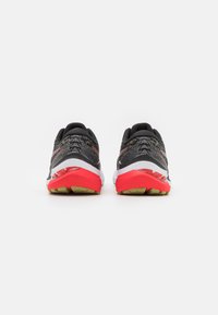 Schwarze und graue Sportschuhe mit roten Akzenten. Texturiertes Obermaterial, gepolsterte weiße Zwischensohle und gemusterte Gummisohle.