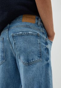 Jeans i ljusblå denim med förstörda detaljer. Har en brun läderetikett på midjan och två bakre fickor med lappar.