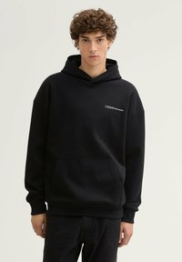 Zwarte hooded sweatshirt met een grote kangaroo zak, manchetten aan de mouwen en een klein bedrukt logo op de borst. Gemaakt van een zachte, gestructureerde stof.