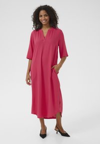 Pink, knee-length dress with a notch collar, three-quarter sleeves, and side pockets. Made of smooth fabric with a loose fit.
