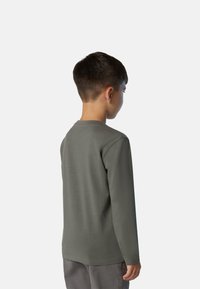 Camisa gris de manga larga hecha de algodón suave. Presenta un escote redondo y un corte regular. Modelo mostrado de espaldas.