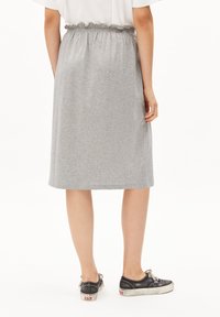 Gray, knee-length skirt made of soft cotton blend, featuring an elastic waistband with ruffled accents. Paired with black canvas sneakers.