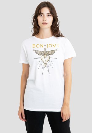 White cotton t-shirt featuring a graphic print of a heart with wings and a sword, with "BON JOVI" text above in gold. Short sleeves.