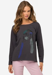 Camisa de manga larga gris oscuro con una colorida impresión gráfica en turquesa, azul y gris. Tejido suave con cuello redondo y corte relajado.