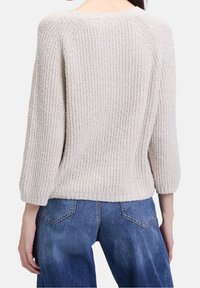 Light beige textured sweater with a ribbed design and three-quarter sleeves, shown from the back, paired with blue denim jeans.