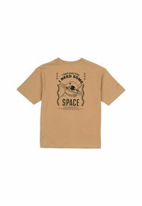 Beige katoenen T-shirt met een geprinte grafische ontwerp met de tekst "IK HEB RUIMTE NODIG" en een illustratie van een planeet. Korte mouwen, ronde hals.