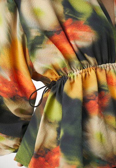 Bluză multicolor cu modele florale abstracte. Fabricată dintr-un material ușor, are talie strânsă cu un șnur negru.