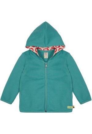 Felpa con zip di colore turchese, caratterizzata da un esterno testurizzato e un rivestimento interno della cappuccio con una fantasia floreale rossa. Include un'etichetta sull'orlo.