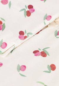 Katoenen stof met een witte achtergrond en kleine, kleurrijke bessenpatronen in roze en rood, omringd door groene bladeren.