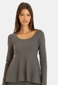 Szary, długi rękaw, top z rozkloszowanym dołem, wykonany z fakturowanej tkaniny i ozdobiony równomiernie rozmieszczonymi metalowymi ćwiekami z przodu.