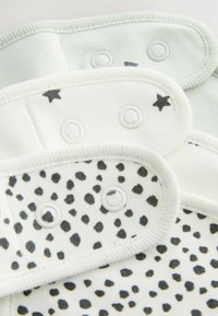 Trois couches en tissu de couleur menthe claire et blanche, présentant un motif à pois et des accents d'étoiles, avec des fermetures à pression et des bords doux.