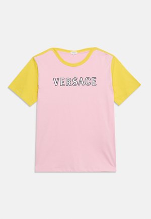 T-shirt à manches courtes avec corps rose, manches jaunes, bordure de col jaune et logo VERSACE imprimé en noir et blanc sur la poitrine.