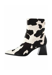 Ankle boot s uzorkom krave s teksturiranim završetkom, šiljastim vrhom i debelim crnim potpeticama. Izrađen od mekog materijala s jedinstvenim uzorkom.