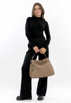 Sac en cuir beige avec un design décontracté, poignée supérieure et poche avant zippée, présenté par un mannequin en tenue noire.