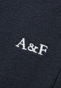Textil azul marino con una textura suave que presenta el logo bordado en blanco "A&F". La tela parece lisa con un color uniforme y un detalle mínimo.