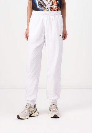 Witte sportieve joggers van lichtgewicht stof, met een elastische tailleband en enkelmanchetten, voorzien van een klein zwart Nike-logo aan de zijkant.