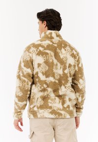 Fleecejakke i beige og creme med et struktureret mønster, høj krave, lange ærmer og en afslappet pasform.