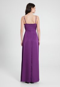 Abito di raso viola con corpetto aderente, sottili spalline regolabili e una lunga gonna fluente. Presenta una zip sul retro e cuciture pulite.