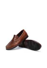 Mocasines de cuero marrón con una banda decorativa, acabado suave y suela de goma plana. El diseño presenta detalles de costura sutiles.