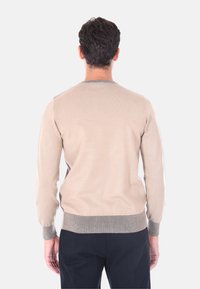 Maglione lavorato a maglia beige con maniche lunghe e scollo rotondo, con orlo e polsini in costina grigia a contrasto. Texture liscia.