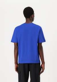 Blauwe T-shirt met korte mouwen en ronde hals, gemaakt van gladde stof. Minimalistisch ontwerp, geen patronen of graphics.