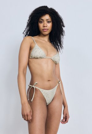 Vaaleanbeige bikinit, joissa on teksturoitu kuvio; kolmionmuotoinen yläosa ja matalavyötäröiset alushousut sivunauhoilla, sileä kangas ja vähäinen peittävyys.