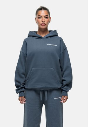 Donkerblauwe oversized hoodie met een buidelzak en een trekkoordcapuchon, met witte tekst "GOODFORNOTHING" op de borst en bijpassende sweatpants.